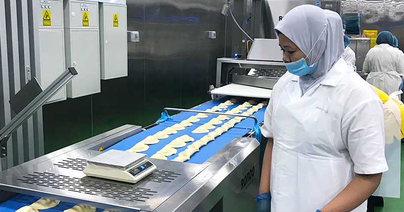 Behind the scenes at Old Chang Kee’s production line: Employees sorting the curry puffs after the dough has been automatically cut and filled
